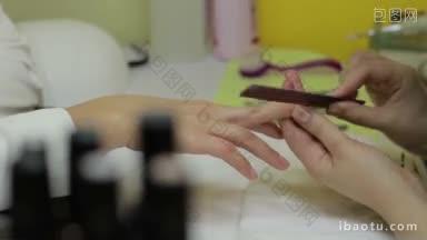 近距离的女人在美甲沙龙接受美甲师用指甲锉修剪指甲美甲大师在美容用指甲锉锉指甲